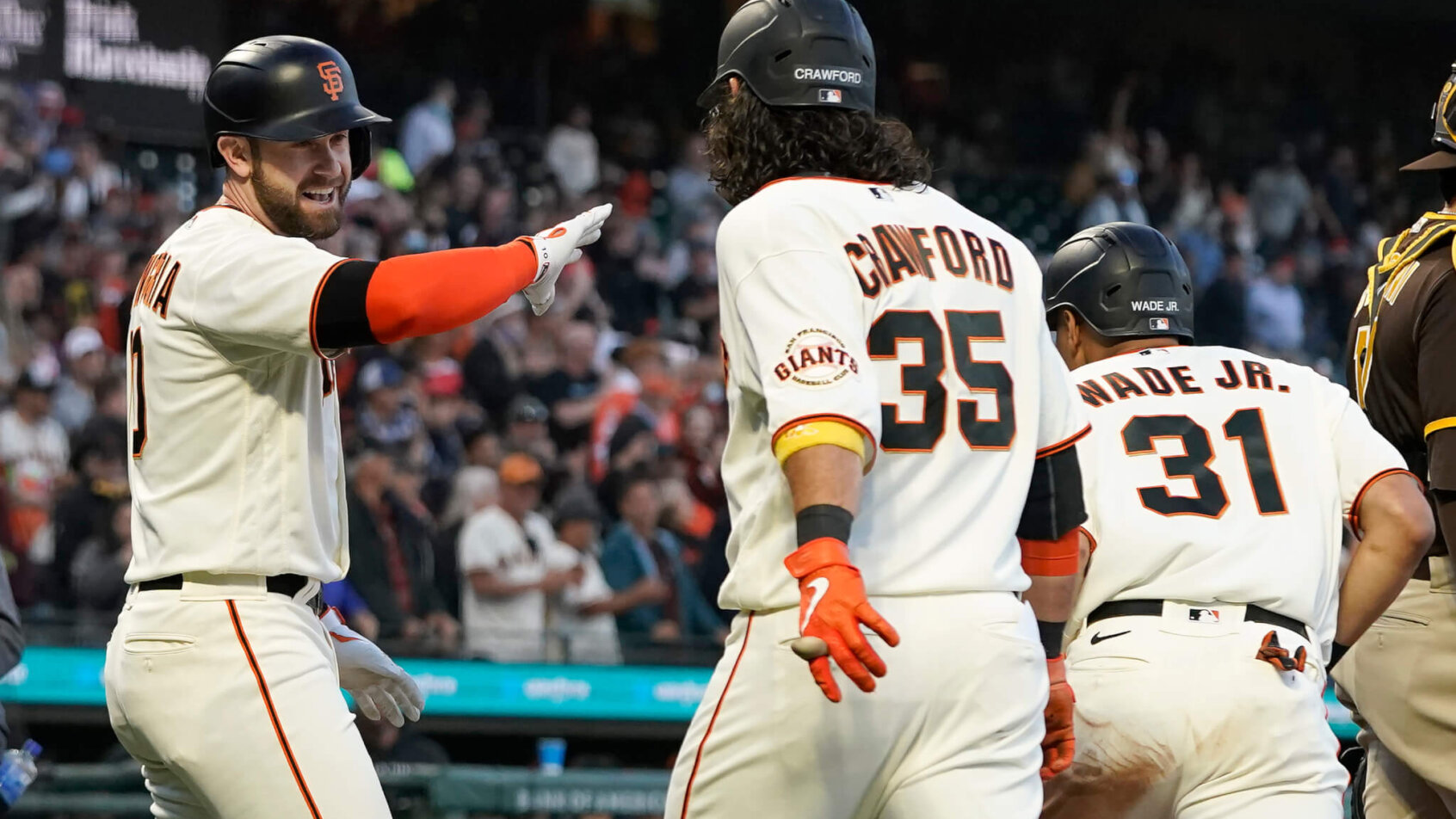 Longoria, Brandon Crawford, and LaMonte Wade Jr. celebrating at home plate