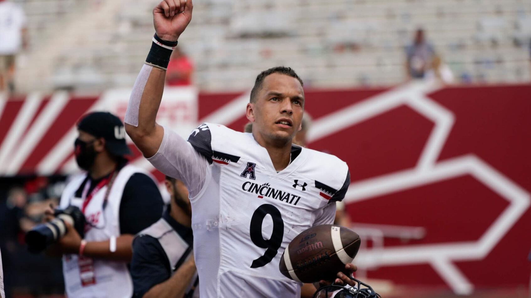 Cincinnati quarterback Desmond Ridder celebrating as he's coming off the field after a college football game.