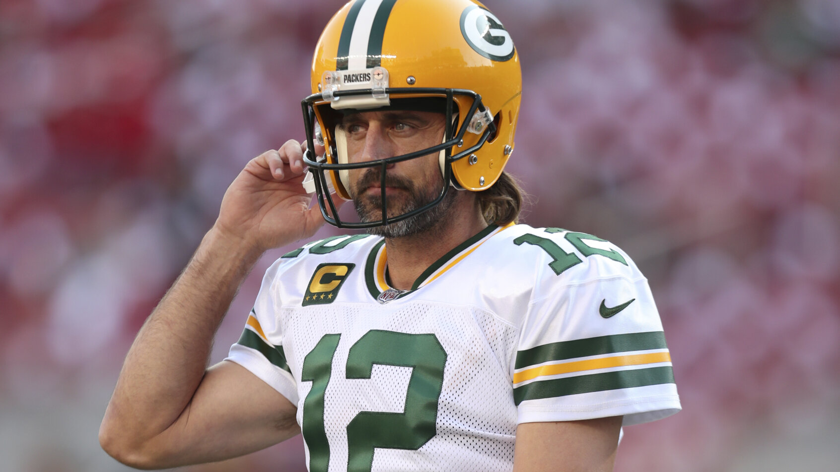 Green Bay Packers quarterback Aaron Rodgers adjusting his helmet before the start of an NFL football game.