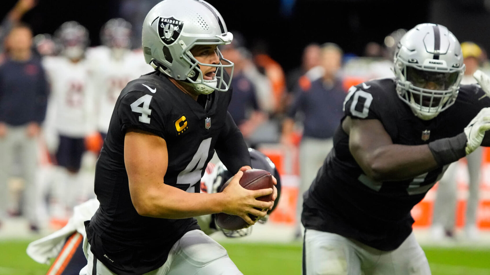 Las Vegas Raiders quarterback Derek Carr running with the ball during an NFL football game.