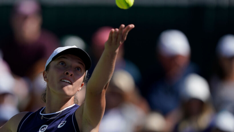 Iga Swiatek serving the ball during a tennis match.
