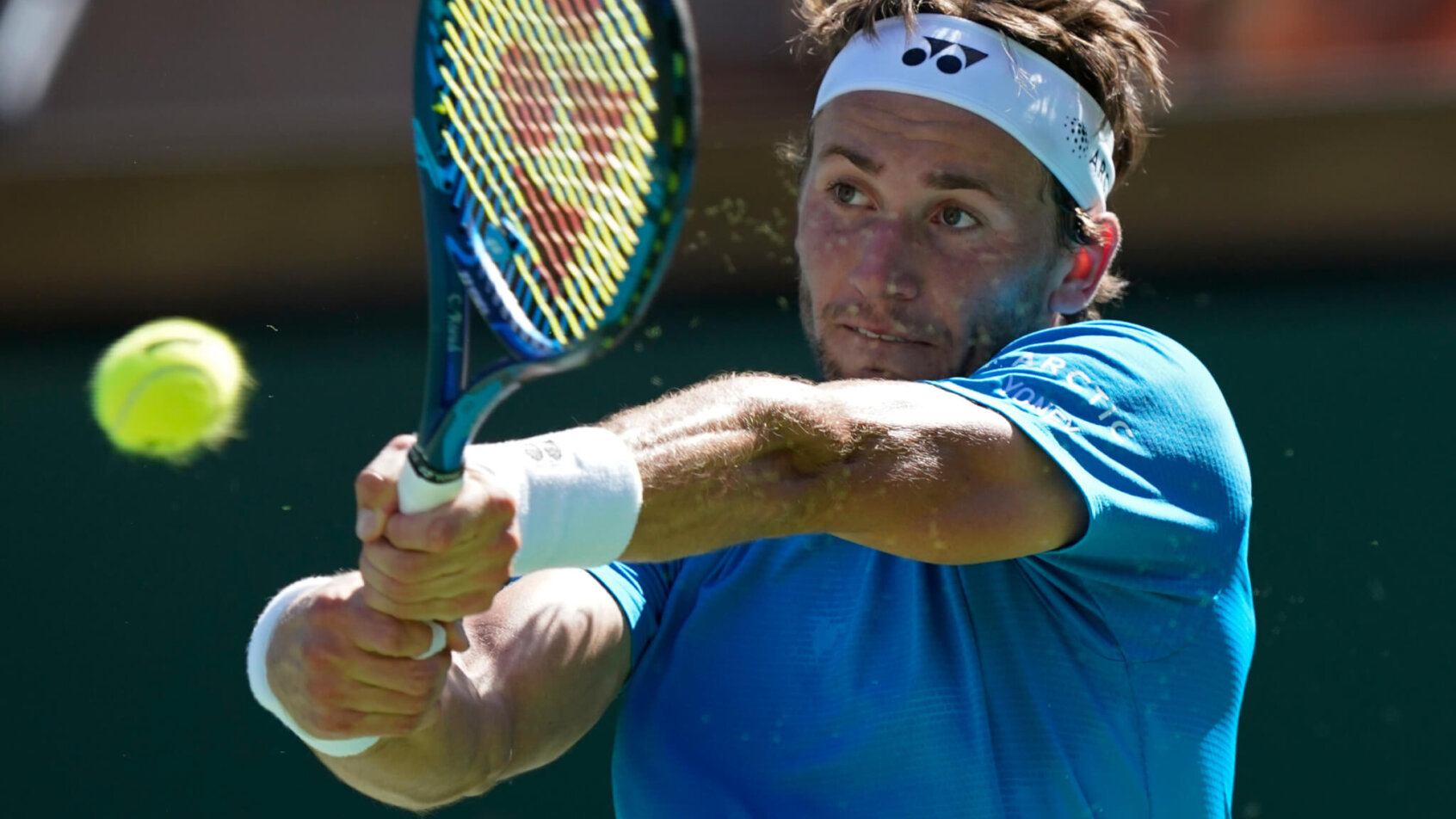 Casper Ruud hitting a return shot during a tennis match.