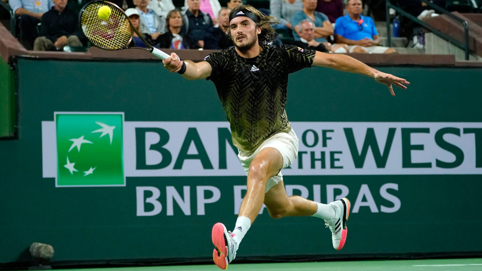 Stefanos Tsitsipas hitting a return shot during a tennis match.