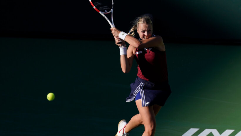 Anett Kontaveit hitting a return shot during a tennis match.