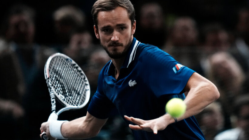 Daniil Medvedev hitting a return shot during a tennis match.