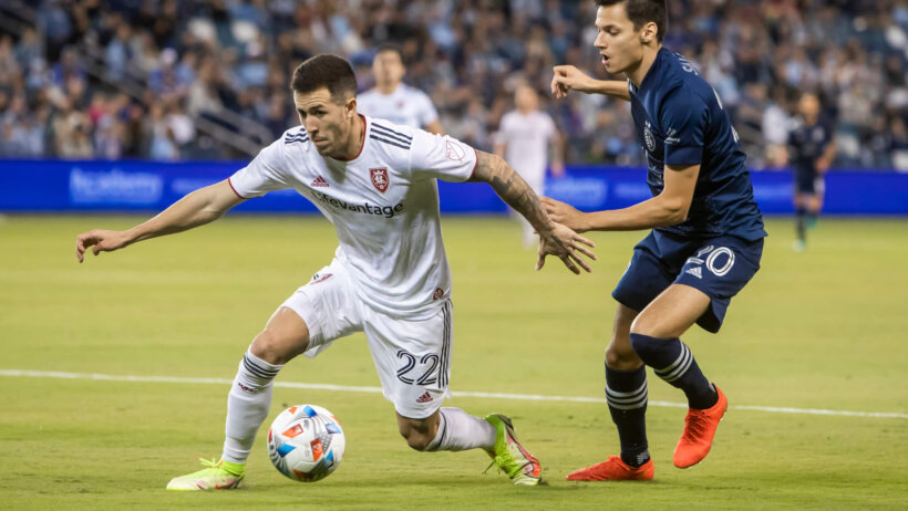 Real Salt Lake defender Aaron Herrera gains control of the ball over Sporting Kansas City forward Daniel Salloi during the first half of a soccer match.