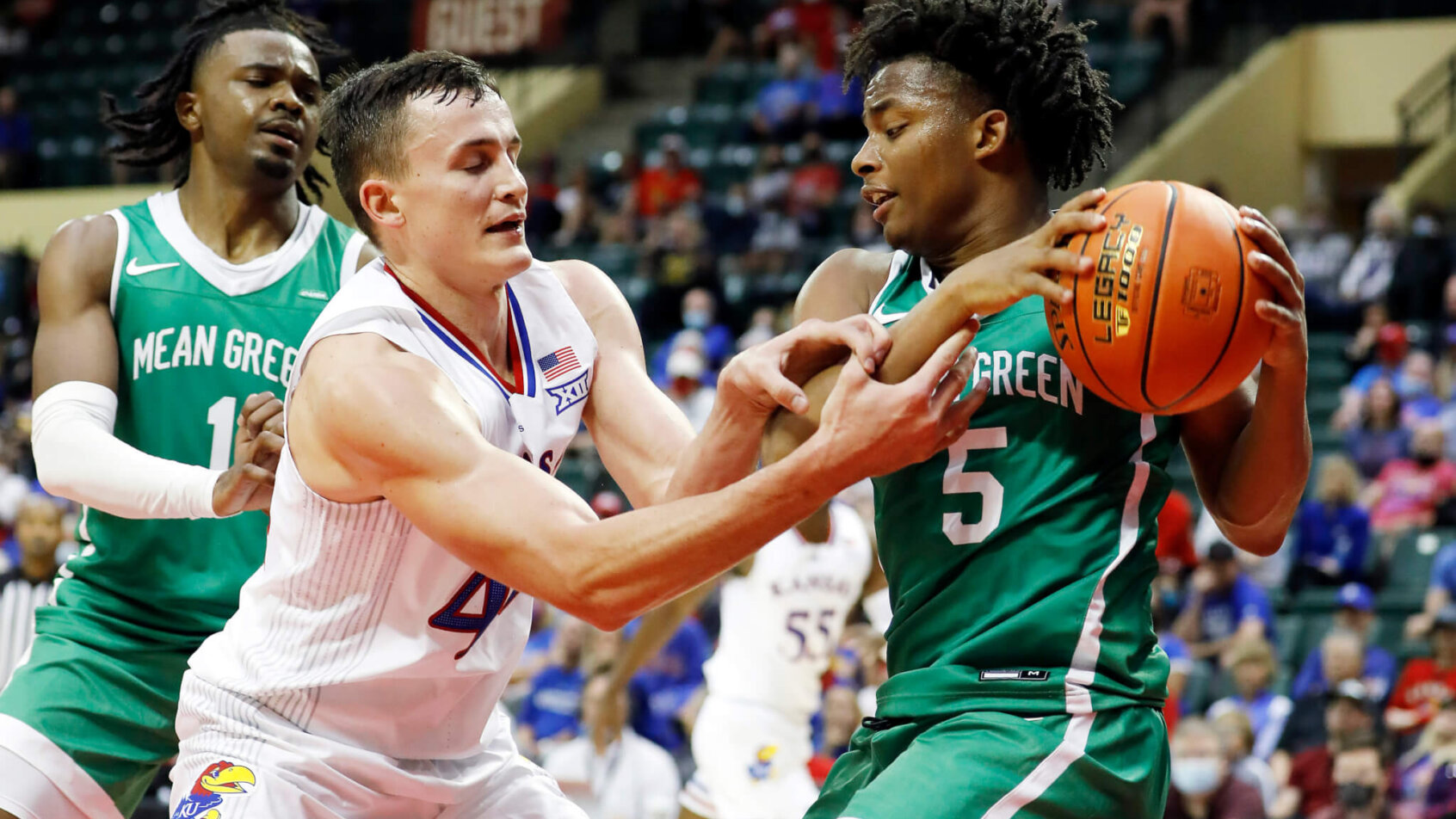 North Texas guard Tylor Perry fighting for the ball with Kansas' Mitch Lightfoot