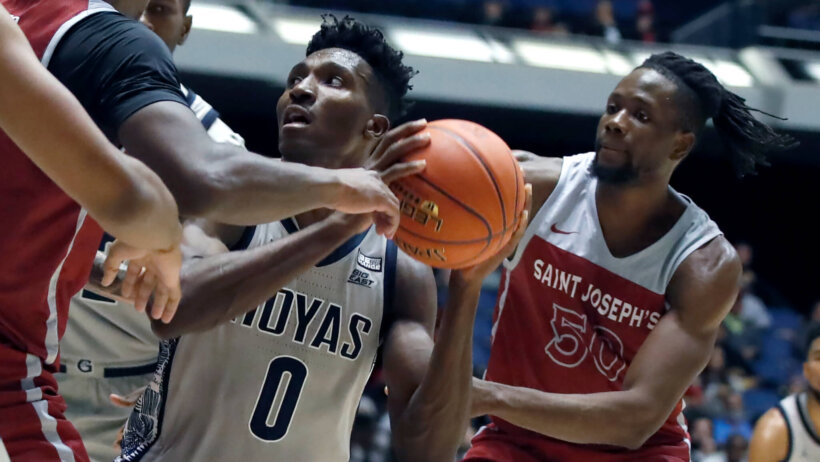 Aminu Mohammed holding ball, surrounded by two defenders