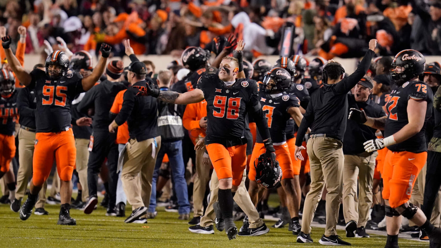 Oklahoma State players celebrating on the field during a football game.