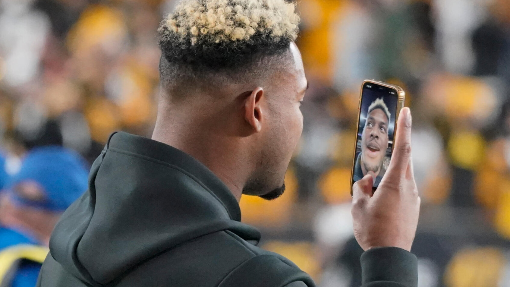 Pittsburgh Steelers wide receiver JuJu Smith-Schuster facetiming on his phone on the field.