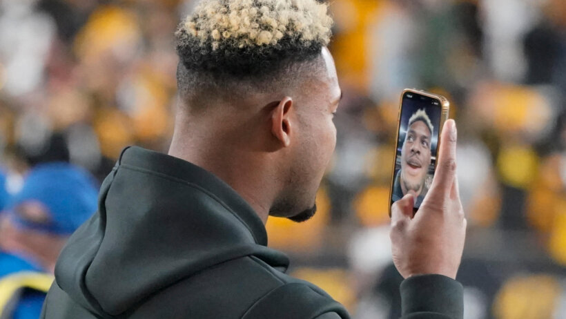 Pittsburgh Steelers wide receiver JuJu Smith-Schuster facetiming on his phone on the field.