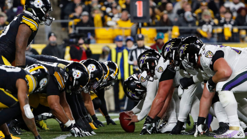 The Baltimore Ravens and the Pittsburgh Steelers lining up at the line of scrimmage.