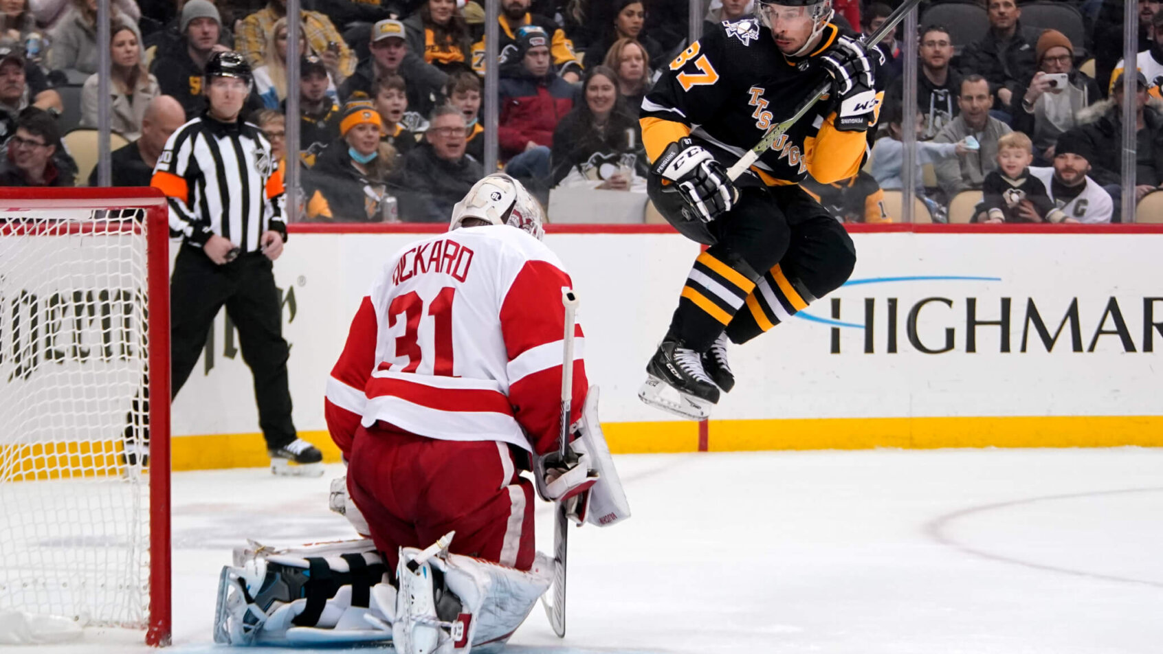 Sidney Crosby leaping to avoid a shot during an NHL game.