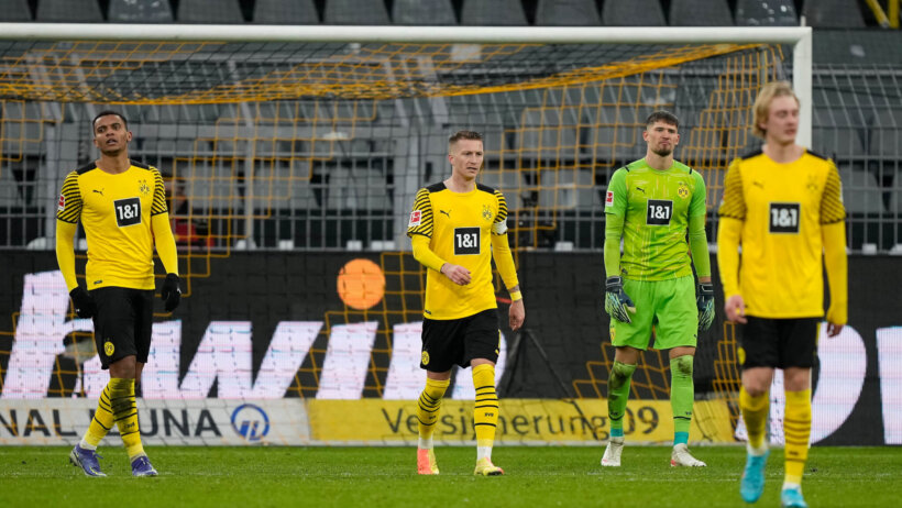 Dortmund players looking disappointed after being scored on during a match.