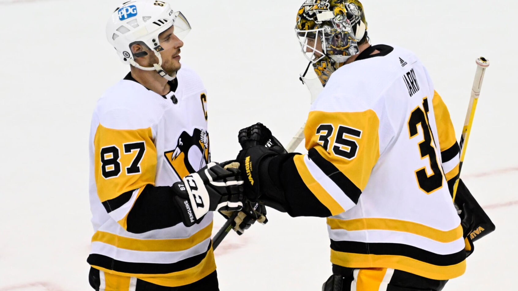 Pittsburg Penguins goaltender Tristan Jarry celebrating with Sidney Crosby on the ice after winning the game.