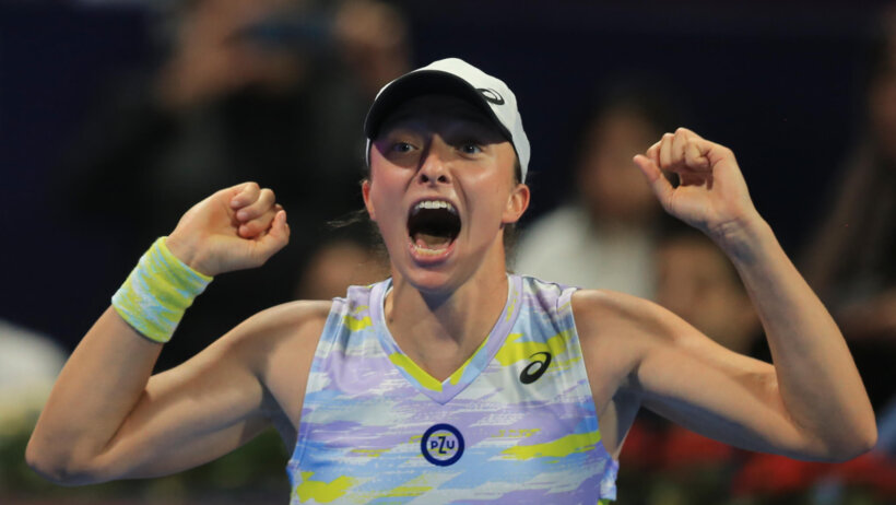 Iga Swiatek celebrating after winning a tennis match.