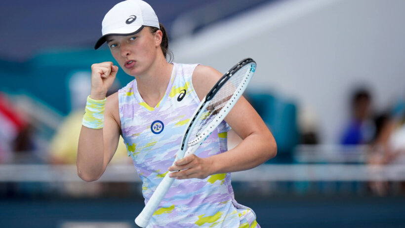 Iga Swiatek celebrating with a fist pump during a tennis match.