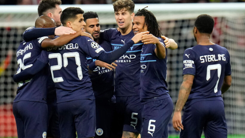 Manchester City players celebrating on the field after winning a match.
