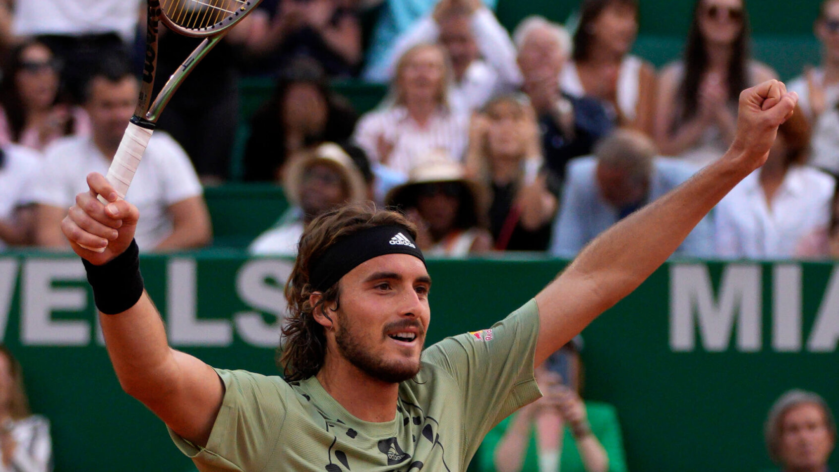 Stefanos Tsitsipas celebrating with his hands up in the air after a win.