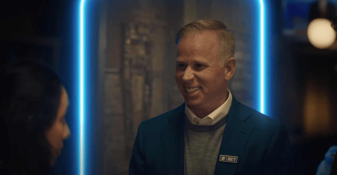 Gerry Dee Score Bet badge blue jacket