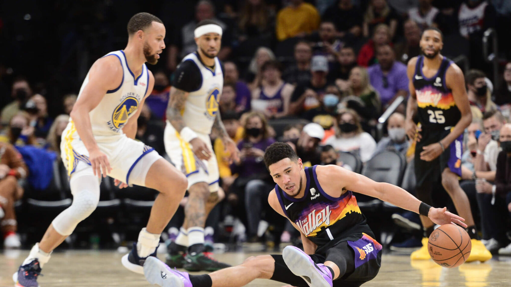 Devin Booker slips with Steph Curry looking on