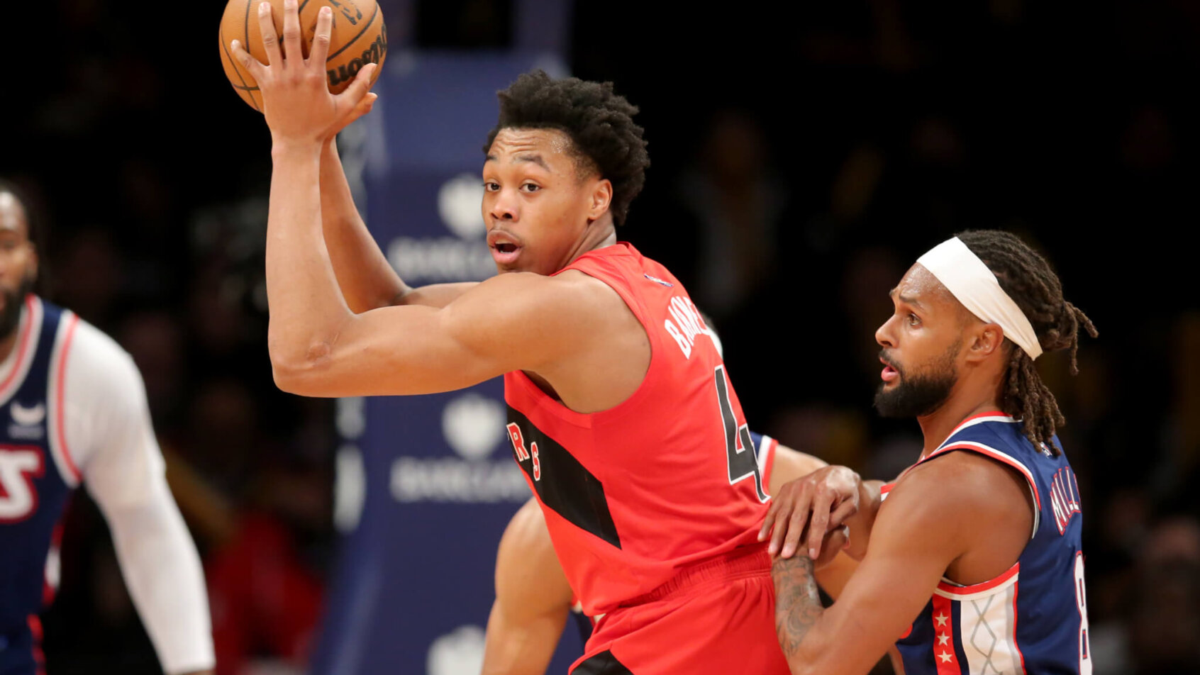 Scottie Barnes holding ball up high with defender on his back