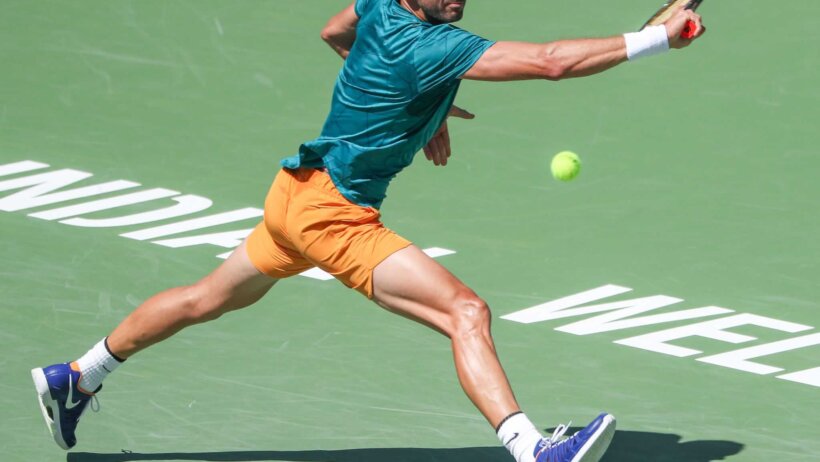 Grigor Dimitrov running down a backhand shot during a match.