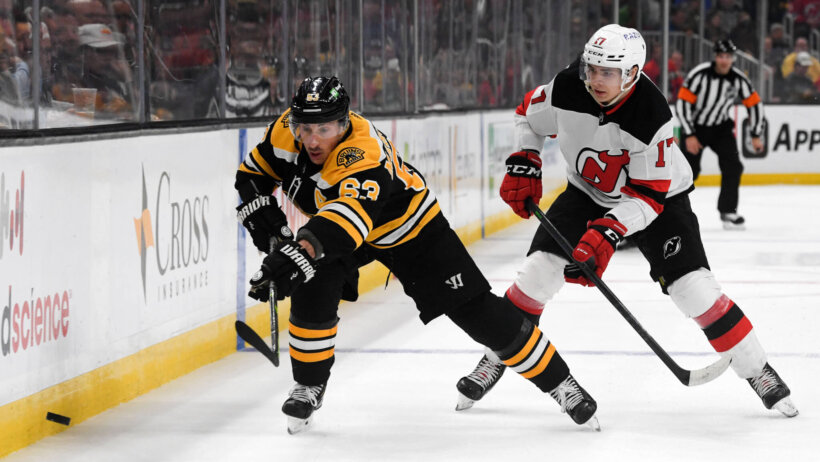 Boston Bruins left wing Brad Marchand and New Jersey Devils center Yegor Sharangovich battle for puck