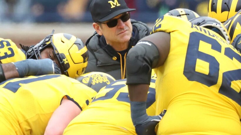Jim Harbaugh huddles with his players
