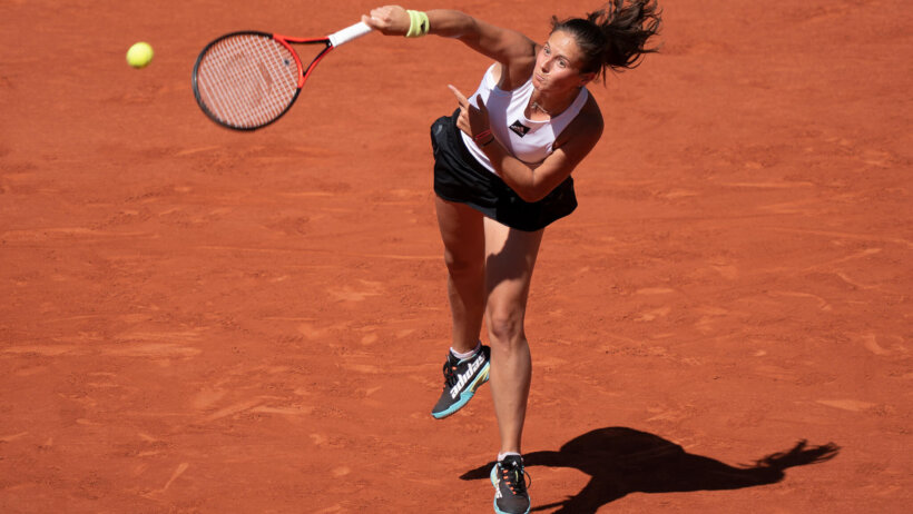 Daria Kasatkina serving a ball during a tennis match.