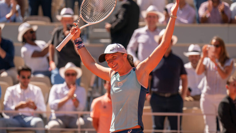 Iga Swiatek celebrating with her hands in the air.