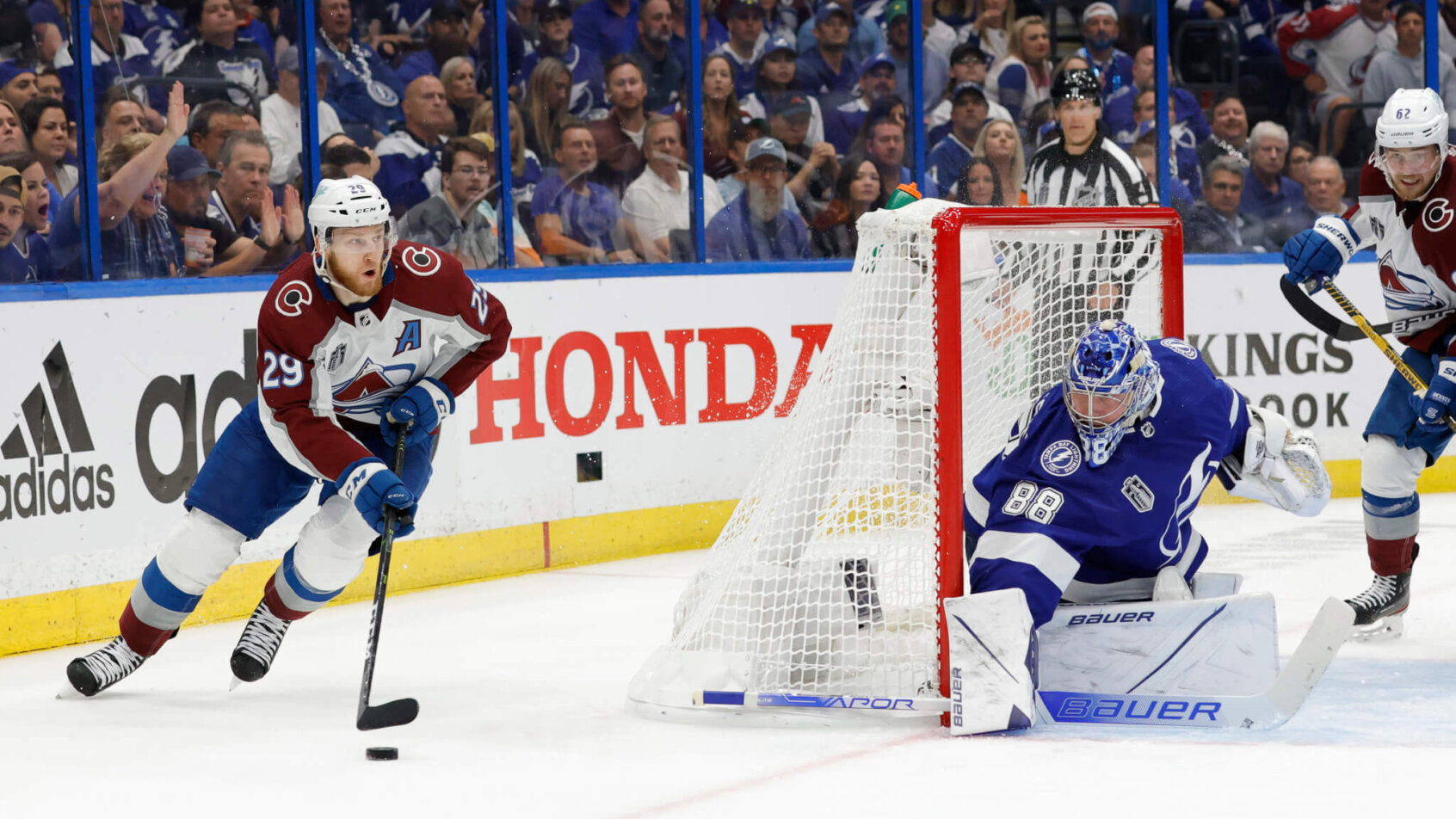 Colorado Avalanche center Nathan MacKinnon skating behind the Tampa Bay net