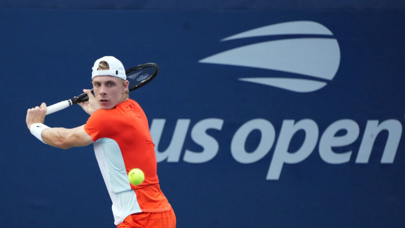 Denis Shapovalov hitting a backhand return during a tennis match.