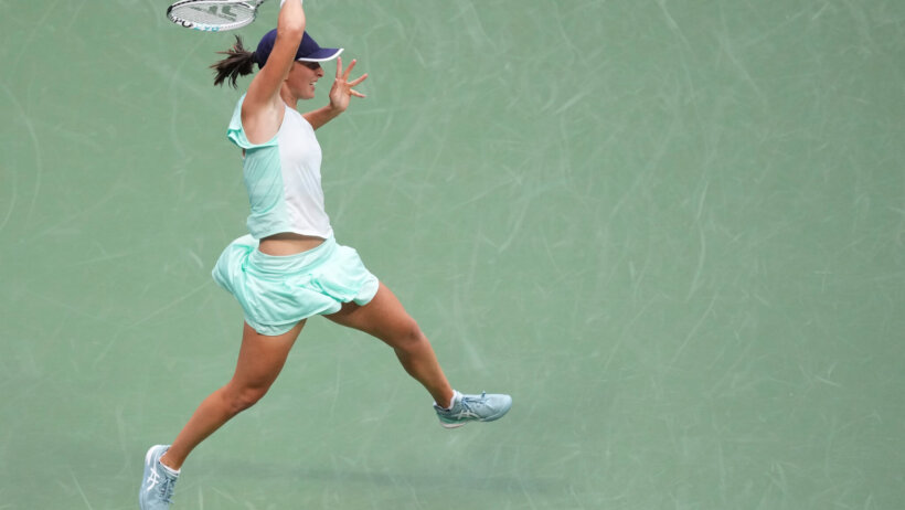 Iga Swiatek hitting a ball during a tennis match.