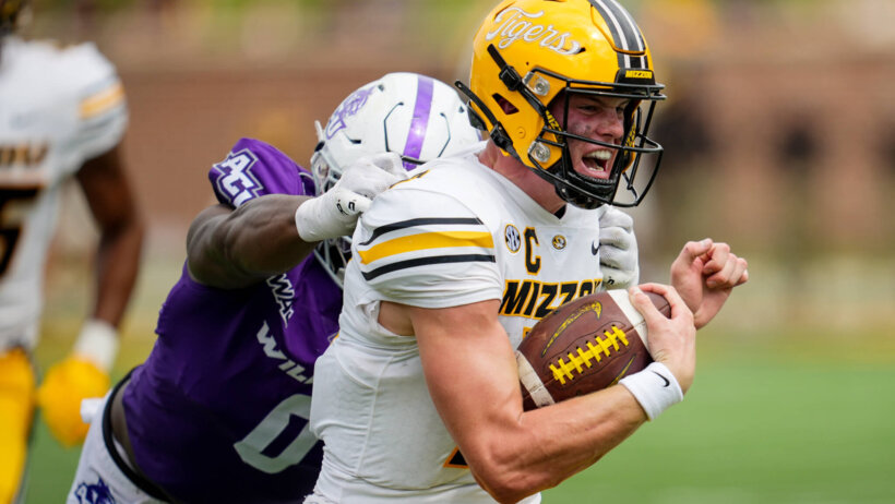 Brady Cook running with ball, grabbed by defende
