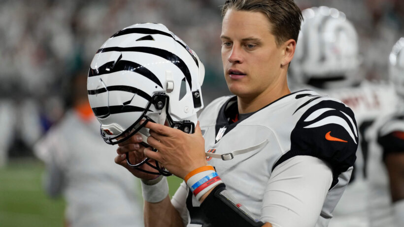 Joe Burrow Cincinnati Bengals putting helmet on white jersey