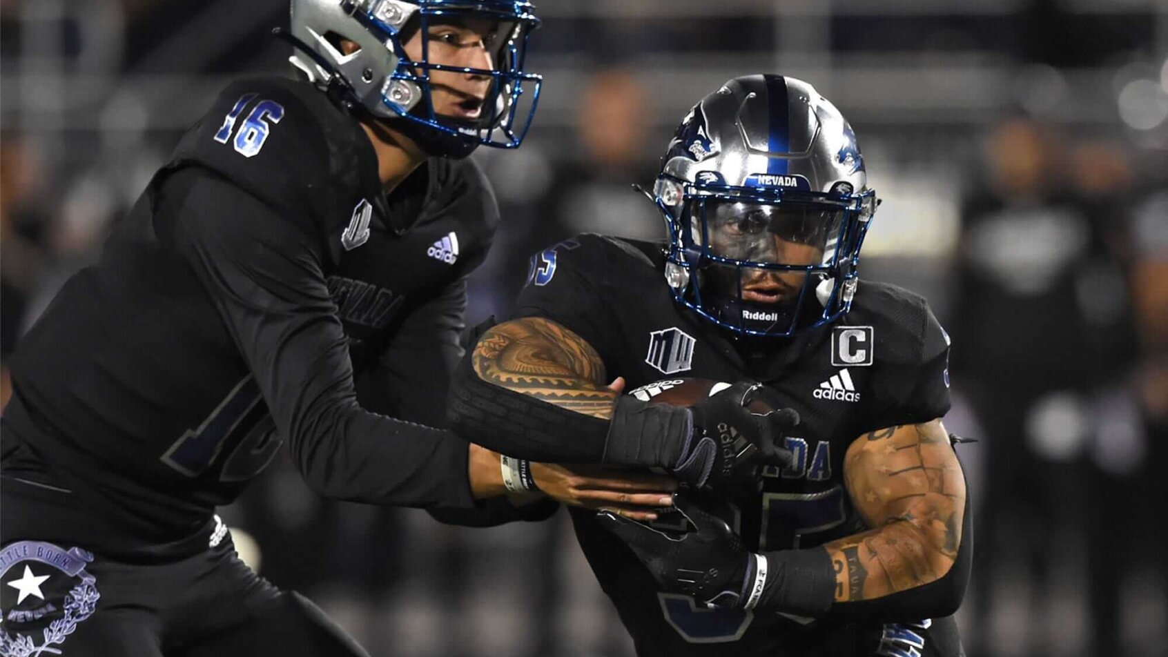 Nevada's Mate Coxs hands the ball off to Toa Taua