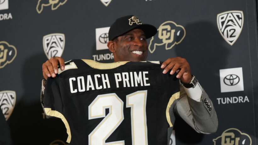 Deion Sanders holds up a Coach Prime jersey