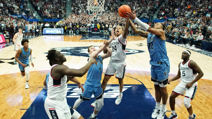 Connecticut Huskies players and Villanova Wildcats players fighting for the rebound.
