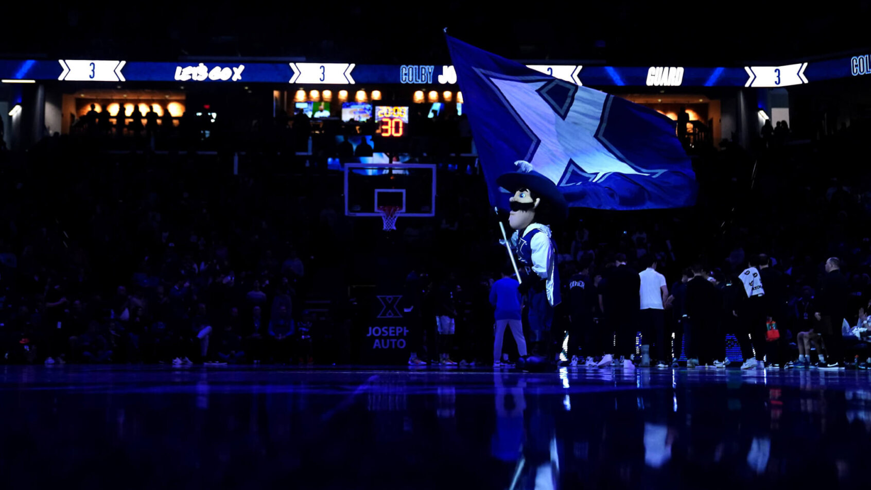 D'Artagnan, the Xavier Musketeers mascot, waving a flag