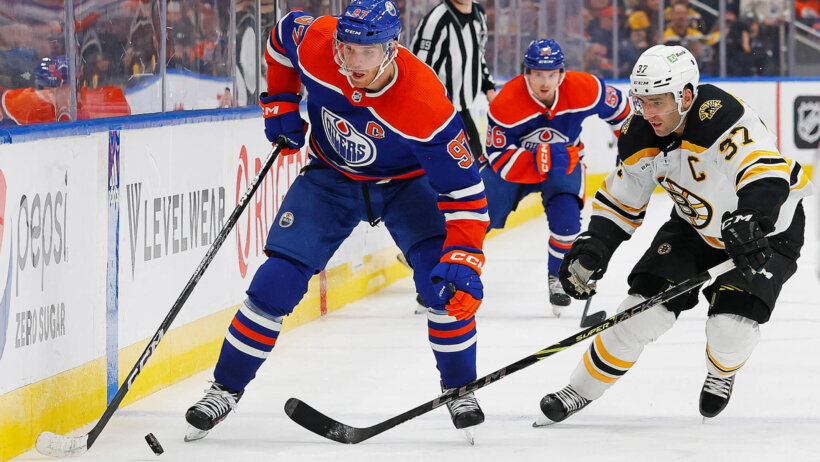 Connor McDavid with puck, checked by Patrice Bergeron