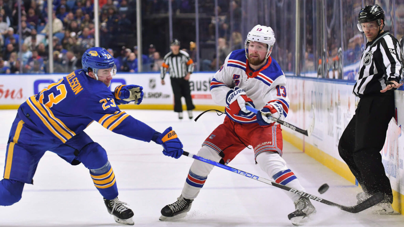 Rangers left wing Alexis Lafrenière passes the puck past Buffalo Sabres defenseman Mattias Samuelsson