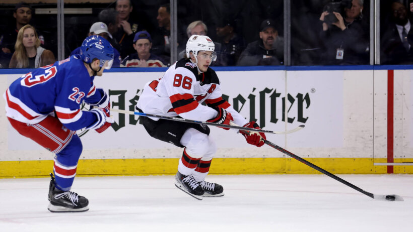 New Jersey Devils center Jack Hughes skates with the puck against New York Rangers defenseman Adam Fox