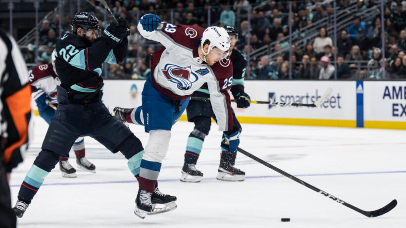 Seattle Kraken forward Oliver Bjorkstrand collides with Colorado Avalanche forward Nathan MacKinnon