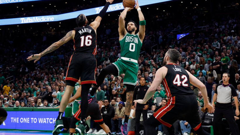 Jayson Tatum shoots over a pair of Heat defenders