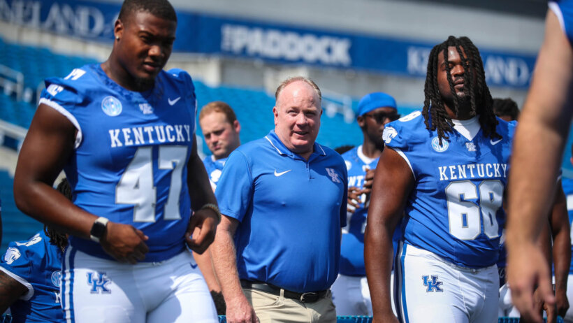 Kentucky Wildcats football coach Mark Stoops with players blue uniforms