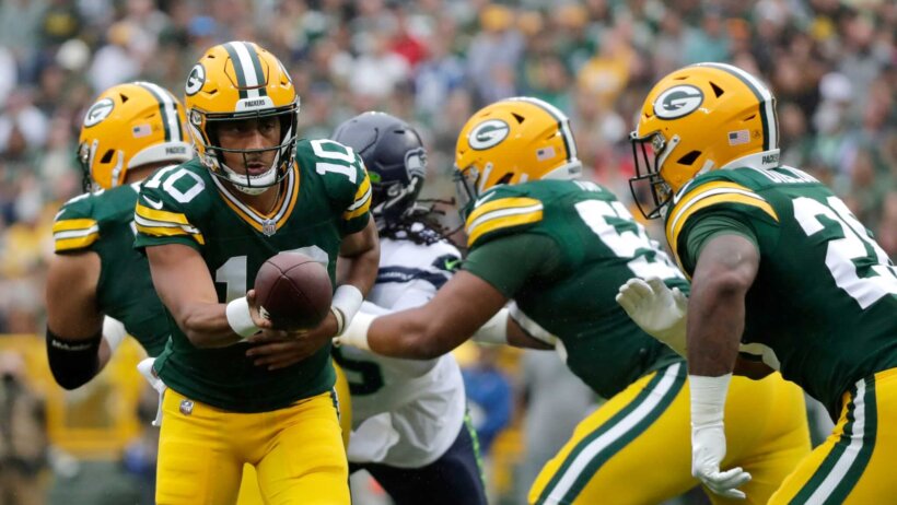 Green Bay Packers quarterback Jordan Love (10) hands off the ball during their preseason football game.