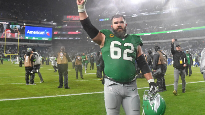 Philadelphia Eagles player Jason Kelce walking hand raised green jersey