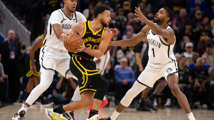 Golden State Warriors guard Stephen Curry looks to pass out of a double team against the Brooklyn Nets