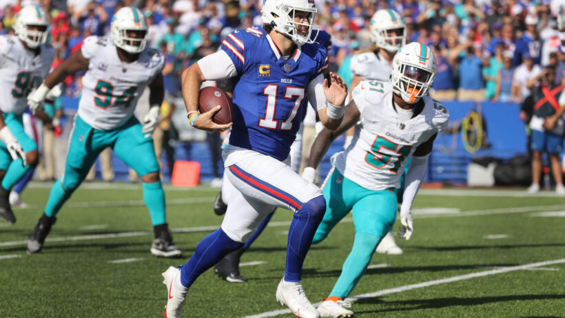 Bills quarterback Josh Allen running with the ball past Miami Dolphin defenders